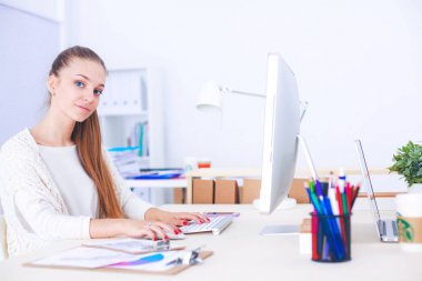 Ofiste çalışan genç bir kadın, masada oturuyor.