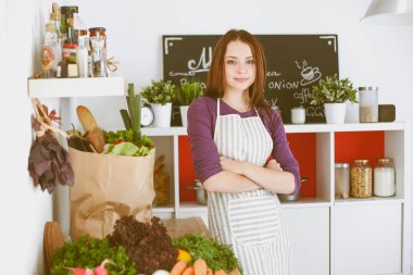 Onun mutfak masa alışveriş torbaları ile yakın duran genç kadın