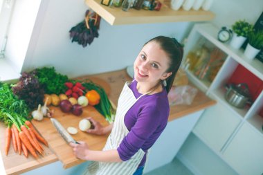 Mutfakta sebze doğrayan genç bir kadın.
