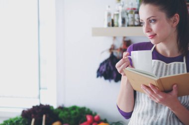 Mutfakta yemek kitabı okuyan genç bir kadın yemek tarifi arıyor.