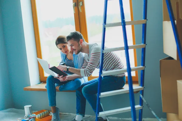 Jong stel zit op de vloer en kijkt naar de blauwdruk van een nieuw huis — Stockfoto