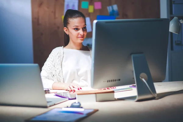 Молодая женщина работает в офисе, сидит за столом — стоковое фото