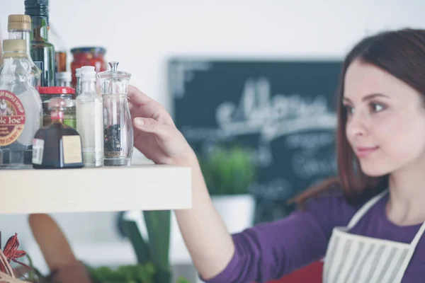 Jovem mulher de pé em sua cozinha perto da mesa com sacos de compras — Fotografia de Stock