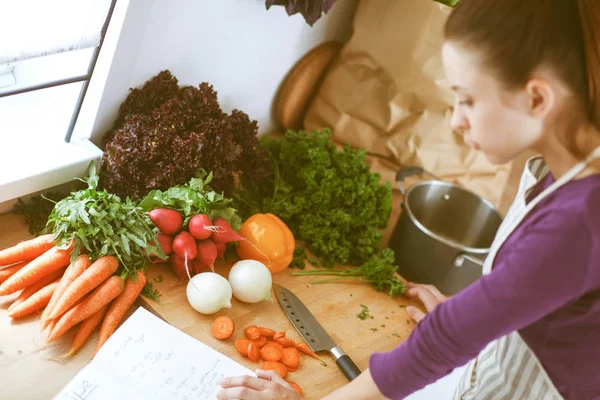 Junge Frau schneidet Gemüse in der Küche — Stockfoto