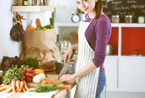 Mujer joven cortando verduras en la cocina —  Fotos de Stock