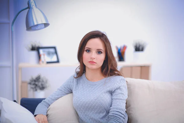 Portrait of happy young woman sitting on sofa — Stock Photo, Image
