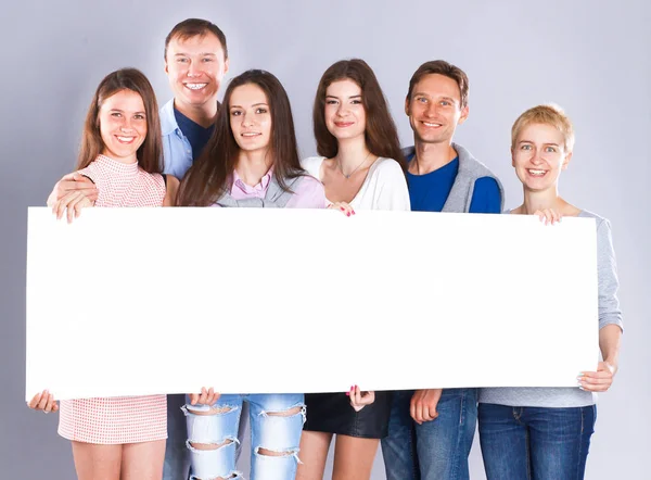 Szczęśliwa młoda grupa ludzi stojąca razem i trzymająca pustkę — Zdjęcie stockowe