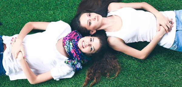 Dos chicas guapas tumbadas en la hierba verde fresca — Foto de Stock