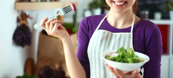 Young woman eating fresh salad in modern kitchen — Stock Photo, Image