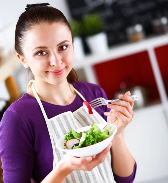Jovem mulher comendo salada fresca na cozinha moderna — Fotografia de Stock