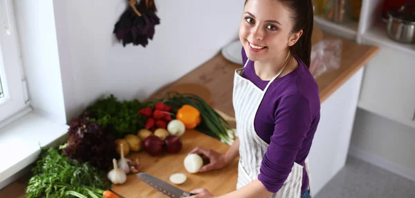 Μια νεαρή γυναίκα κοπή λαχανικά στην κουζίνα. — Φωτογραφία Αρχείου