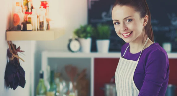 Jonge vrouw staan in haar keuken in de buurt van bureau — Stockfoto