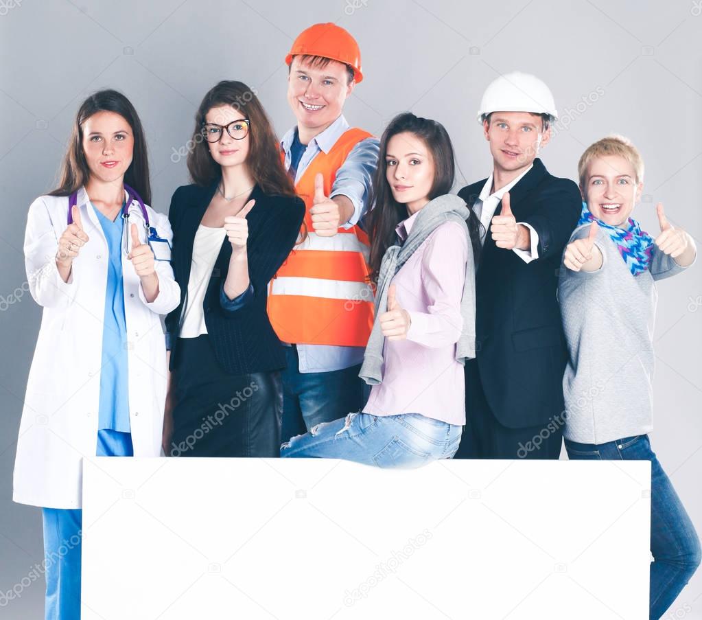 Happy group of people of different professions holding a blank billboard.