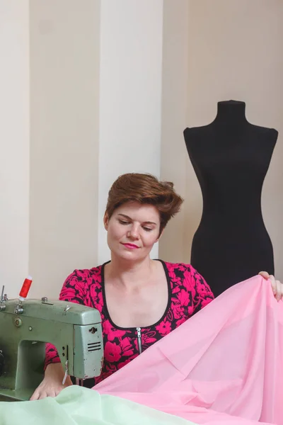 Genç bayan terzi stüdyodaki katalogdan malzeme seçiyor..