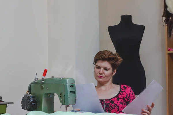 Young female dressmaker choosing material from catalogue in studio. — Stock Photo, Image