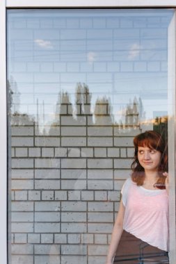 Güzel kız penceresinin arkasına. Camdan bakıyor.