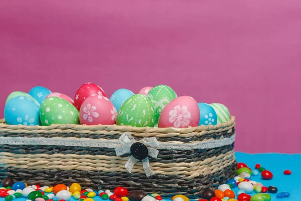 Mavi-pembe arka plan üzerinde sepetteki renkli Paskalya yumurtaları.