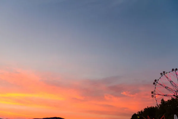 dönme dolap ilçe fuarda gün batımında silüeti.