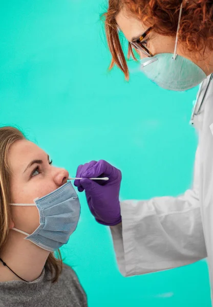 female doctor with mask doing covid-19 test on a young blonde girl