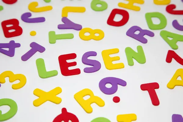 close-up of the german word LESEN - reading - and seamless pattern with letters of the alphabet and numbers in random order on a white background. Education and Back to school concept
