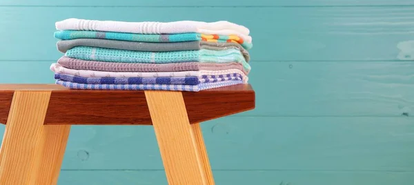 Pile of linen kitchen towels. colorful dish towels stack on a wooden Craft Product stool at wooden background. white copy space for text.