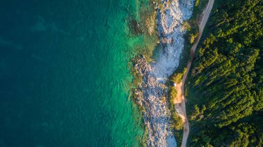 Gün ışığı zümrüt rengi su ile kayalık bir burun resmini uçak