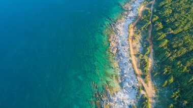 Gün ışığı zümrüt rengi su ile kayalık bir burun resmini uçak