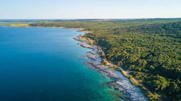 Gün ışığı zümrüt rengi su ile kayalık bir burun resmini uçak