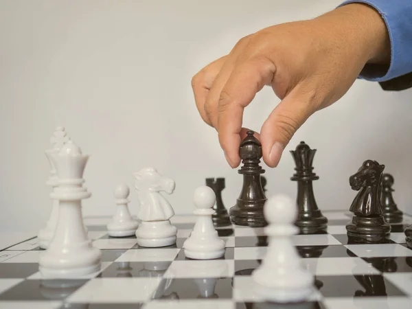 Бізнесмен рука рухає королівську шахову фігуру на борту з білим тлом, виклики планування бізнес-стратегії до концепції успіху — стокове фото