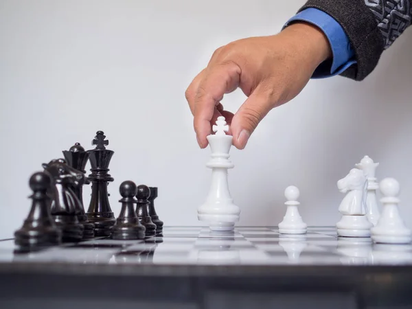 Empresario mano moviendo pieza de ajedrez rey a bordo con fondo blanco, desafía la planificación de la estrategia de negocio al concepto de éxito — Foto de Stock