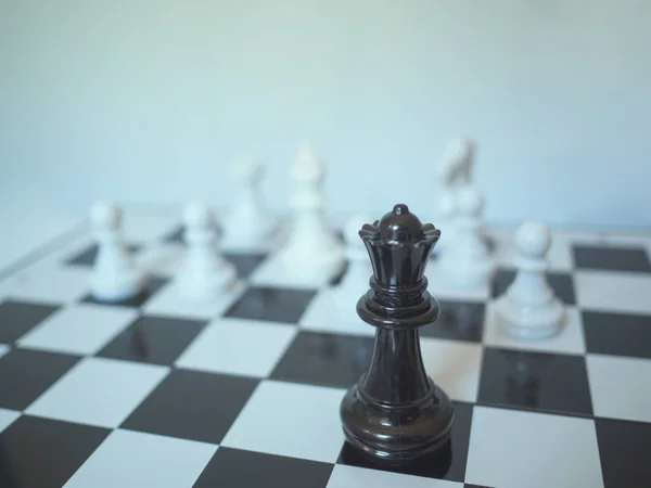 A black chess queen stand in front of white chess enemy on board, challenges planning business strategy to success concept