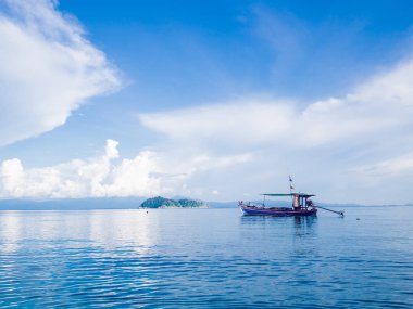 Mavi deniz ve gökyüzünde uzun kuyruklu tekne Güzellik gününde beyaz bulutlarla