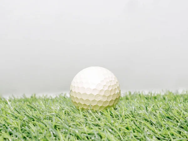 Foto de bola de golfe amarelo na grama artificial com backgro branco — Fotografia de Stock