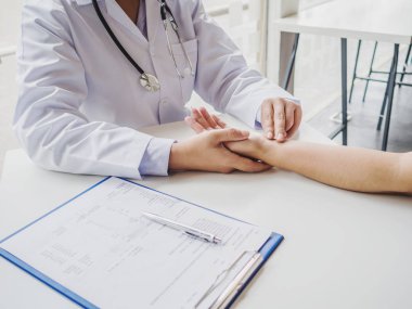 Doktor hastanın nabzını elle kontrol eder ve sonuçları kaydeder.