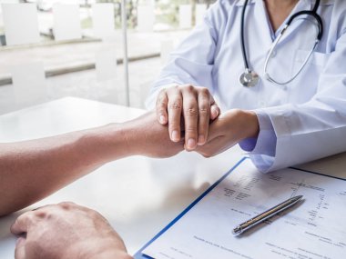 Doktor cesaret vermek için el ele tutuştu ve sağlık muayenesi sonuçlarını hastaya açıkladı.
