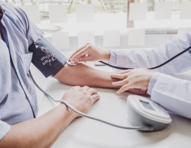Doktor steteskopla hastayı muayene eder ve sonuçları kaydeder.