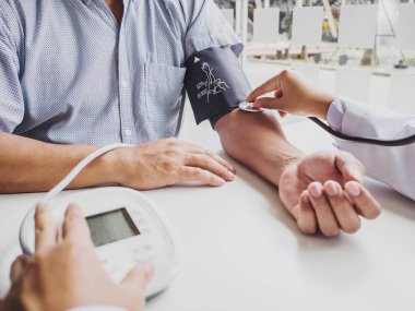 Doktor steteskopla hastayı muayene eder ve sonuçları kaydeder.