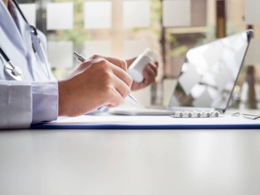 Doktor, hastanın sağlık muayenesi sonuçlarını ve ilaç kullanımını kaydeder.