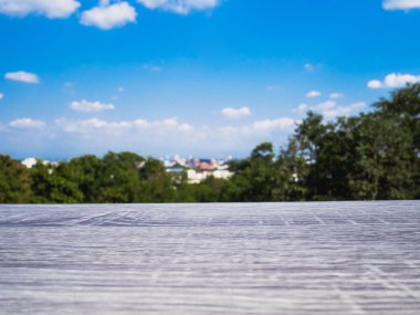 Mavi gökyüzü ve şehir manzarasının önündeki boş ahşap masa