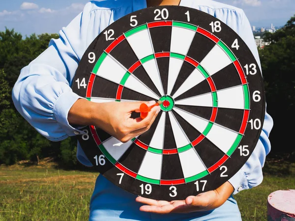 Businesswomen hand holding dart Board on blue sky and city view background, Setting challenging business goals And ready to achieve the goal concept