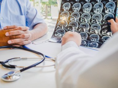 Doktor beyin röntgenini değerlendirir ve hastalara sağlık hizmetlerini tavsiye eder.