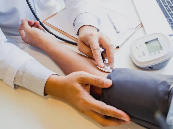 Der Arzt bewertet den Patienten mit Stethoskop, Blutdruckmessgerät und protokolliert die Ergebnisse — Stockfoto