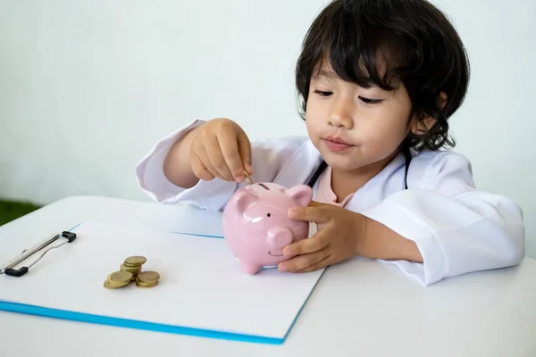 Kid doctor and Medical equipment with pink piggy bank, Saving money for future plan and Health insurance concept.