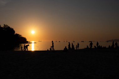 Gün batımını, gün batımını izlemeye gelen insanların gölgesiyle birlikte deniz suyuna..