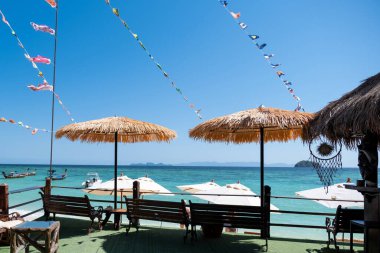 Güneş sığınağı ve mavi deniz manzaralı sandalyeler, tatillerde veya emeklilikten sonra seyahat planları
