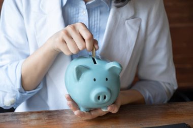 İş kadını, mavi kumbaraya para koyup yeni iş hedefi ve emeklilik konsepti için para biriktiriyor..