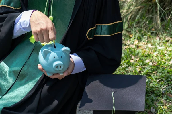 身穿单身汉制服的人正在把硬币存入蓝色储蓄罐 为教育计划和退休基金的概念存钱 — 图库照片