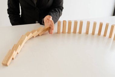 Kadın diğer tahta blokları korumak için ahşap blokları elle durdurur yönetim ve strateji planı riskini kavrar..