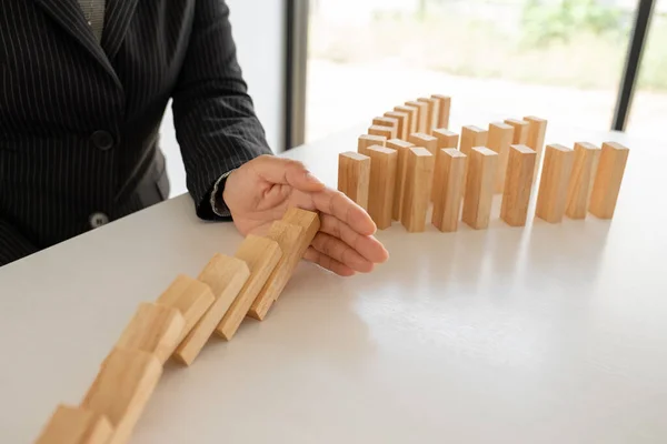 Woman hand stop wooden blocks for protect other wooden block, Concept Risk of management and strategy plan.