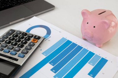 Ofisinde hesap makinesi olan pembe kumbara, yeni iş hedefi ve emeklilik konsepti için biriktiriyor..